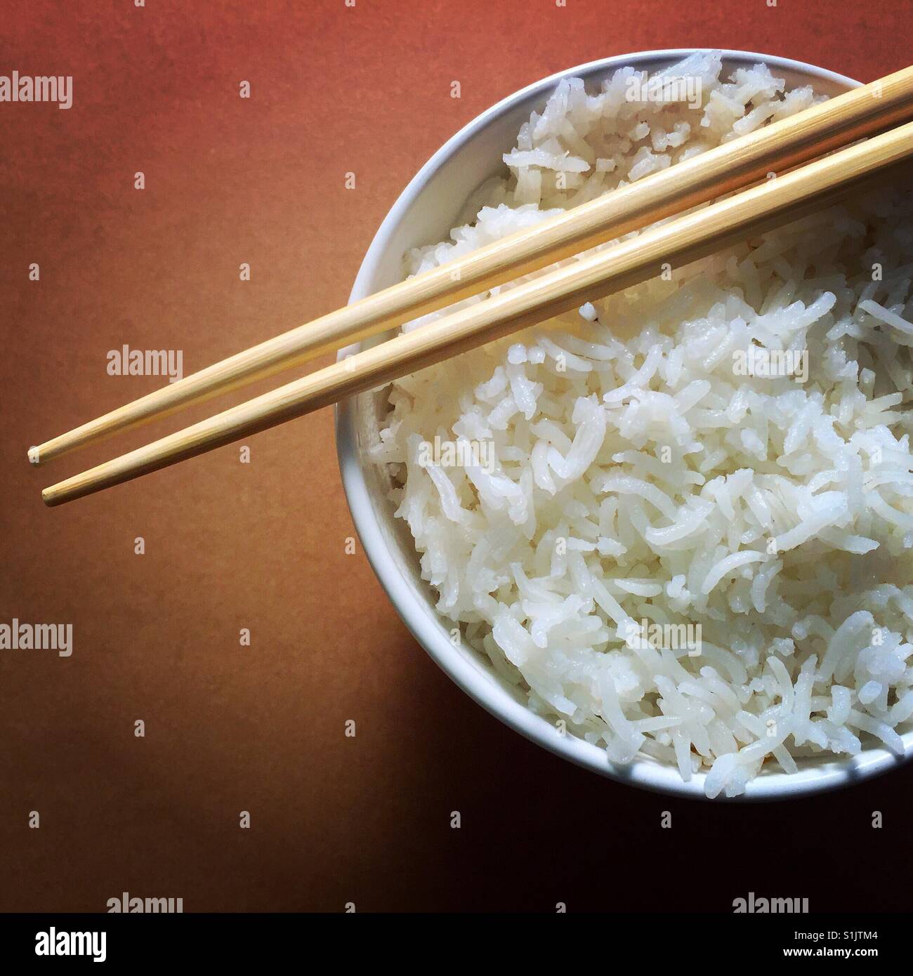 Chopsticks resting on a small bowl of plain white rice Stock Photo