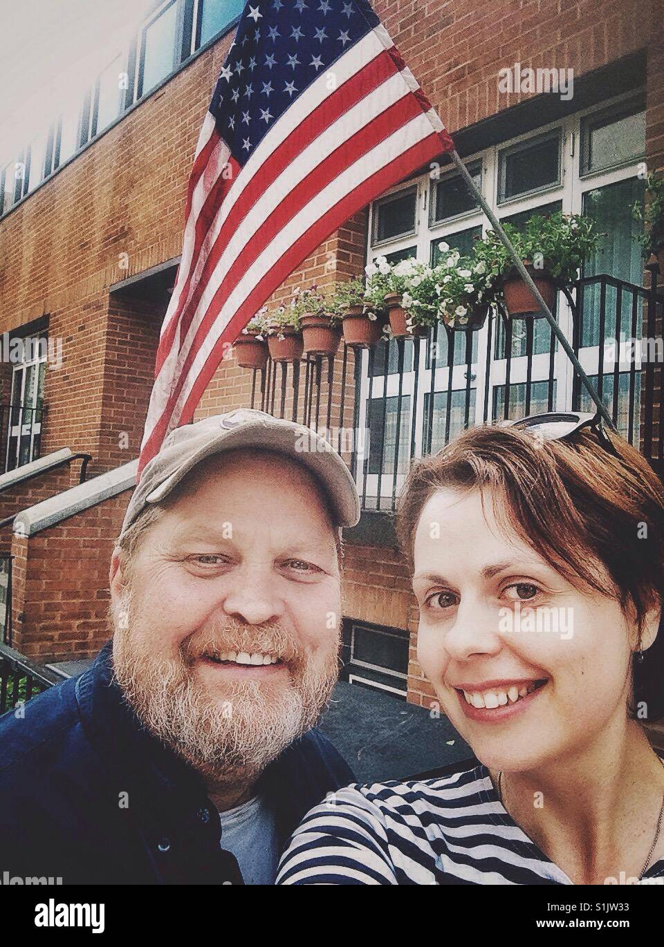 Selfie of a smiling man and woman against of flag of United States on a building - Smartphone Captured Stock Image