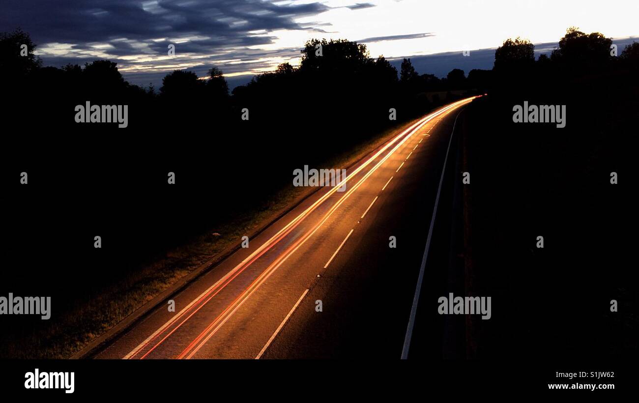 Rear view car light trails through the countryside at twilight - Smartphone Captured Stock Image