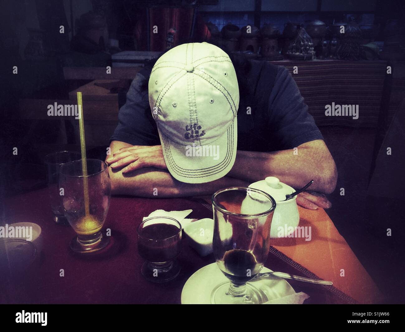 Tired tourist falling asleep at the dinner table in restaurant in Peru Stock Photo