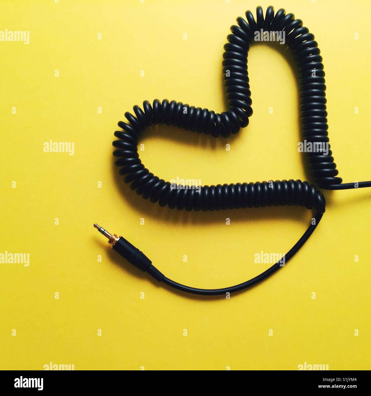 A coiled headphone cable made in to a heart shape on a yellow