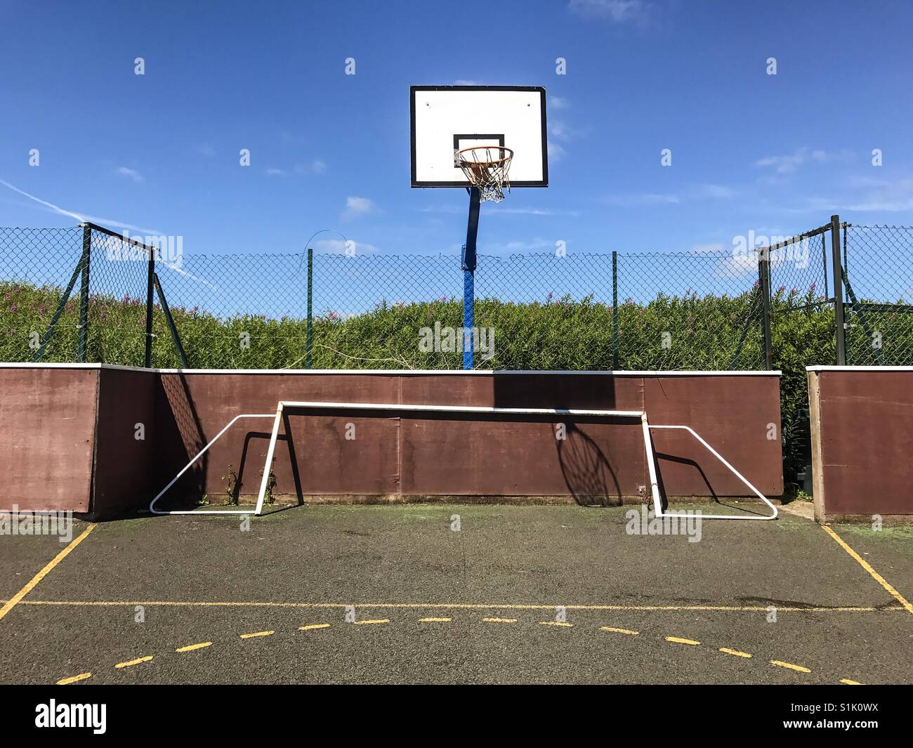 A basketball hoop and a collapsed football goal on a neglected community sports court in England. Stock Photo
