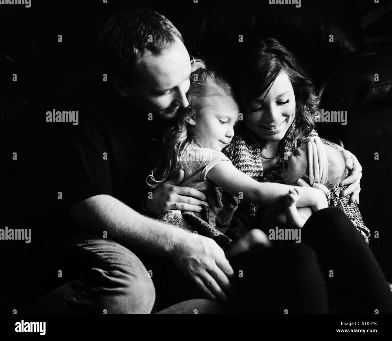 Young happy family with newborn baby and 3 year old girl Stock Photo