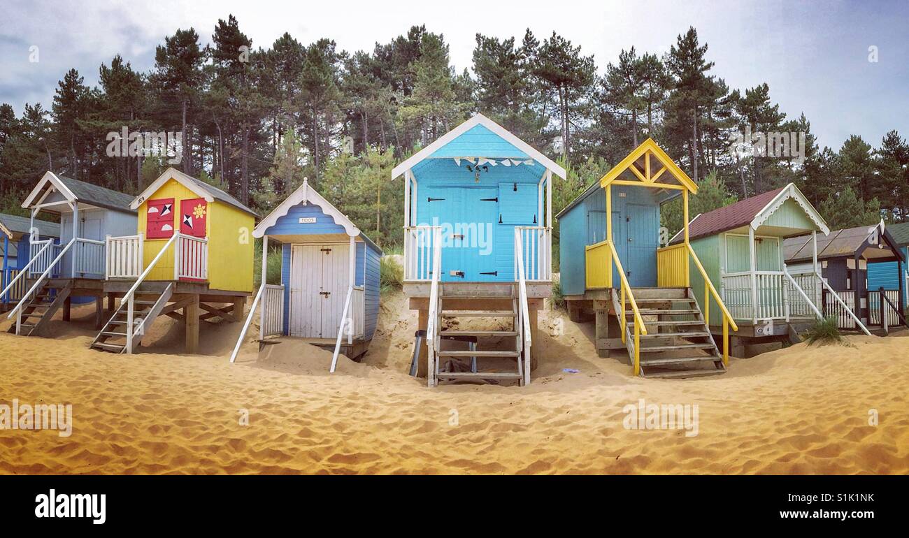 A panoramic image of rows of colourful wooden beach huts on a sandy beach - Smartphone Captured Stock Image