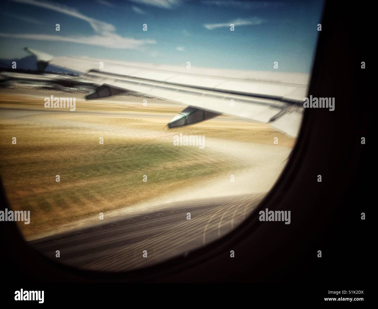 Long exposure looking out of jet plane window at wing and runway during takeoff. - Smartphone Captured Stock Image