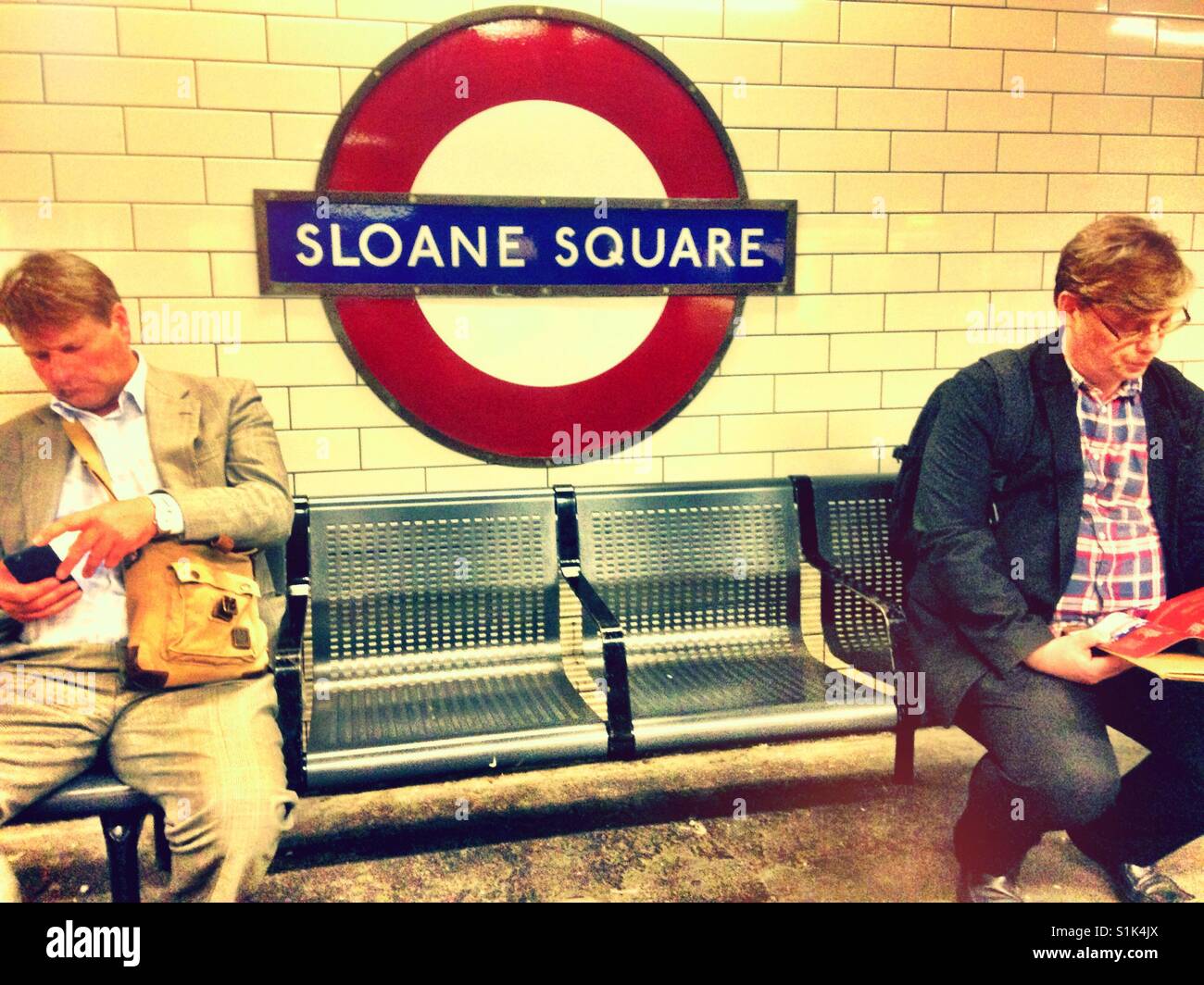 Sitting on a bench at Sloane Square London Underground Station. Stock Photo