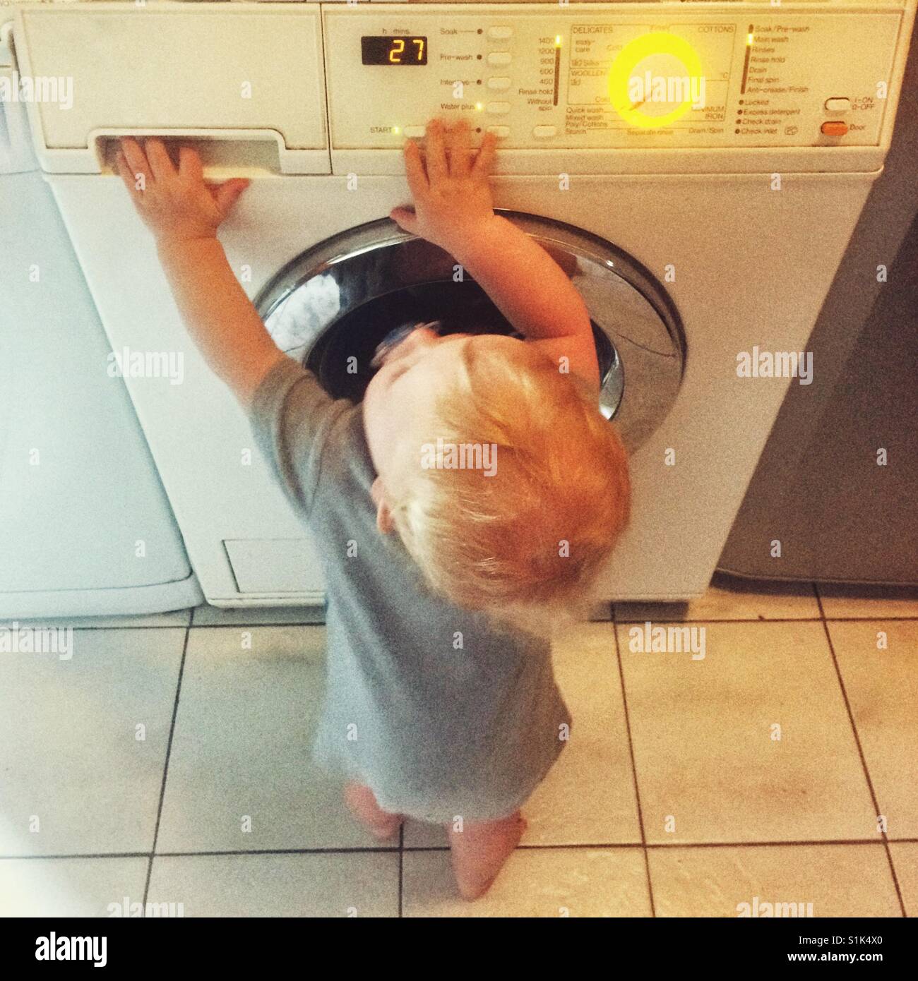Eleven month old baby boy playing with a washing machine - Smartphone Captured Stock Image