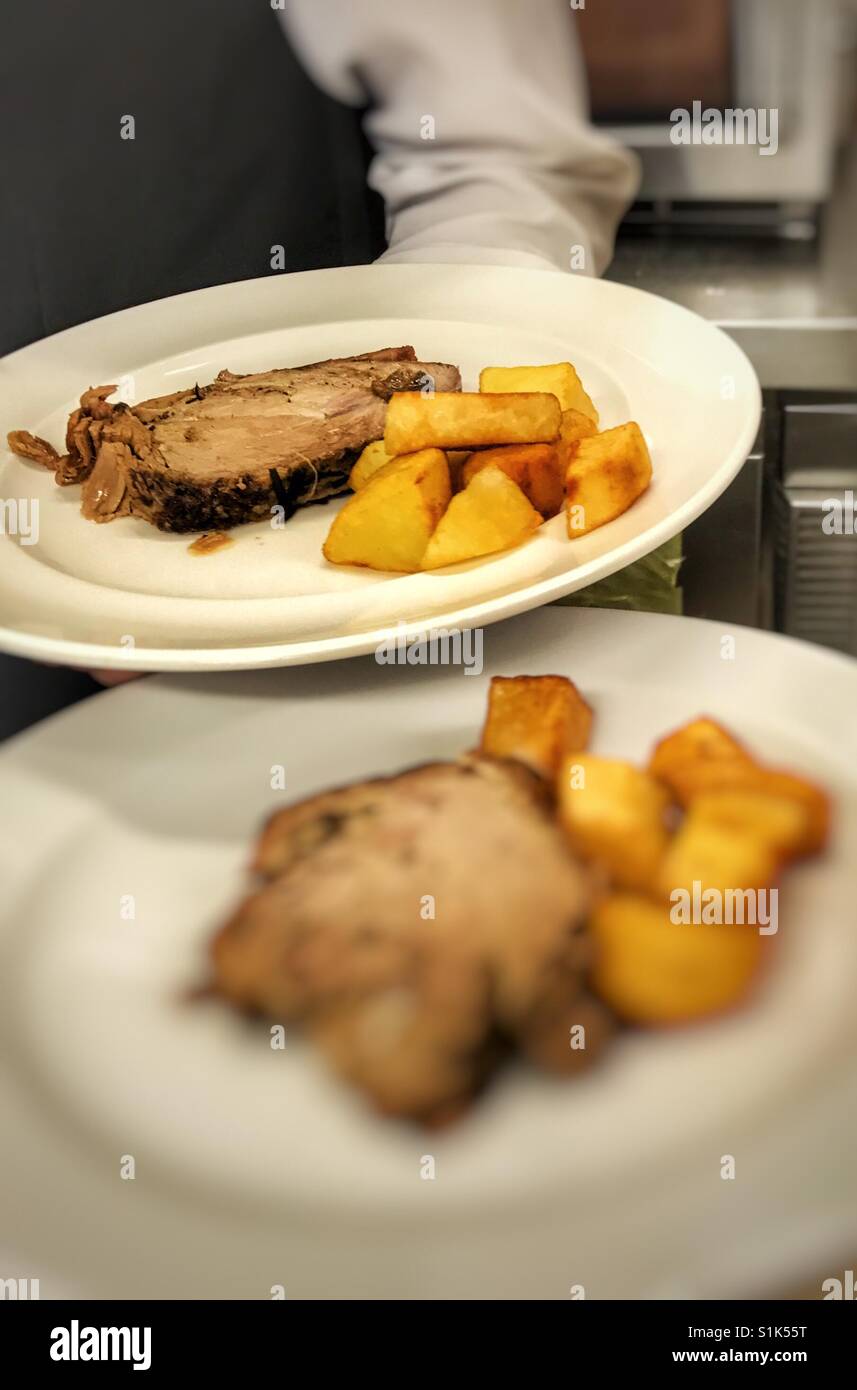 Serving the second course , waiter with meat and potatoes plates in hand Stock Photo