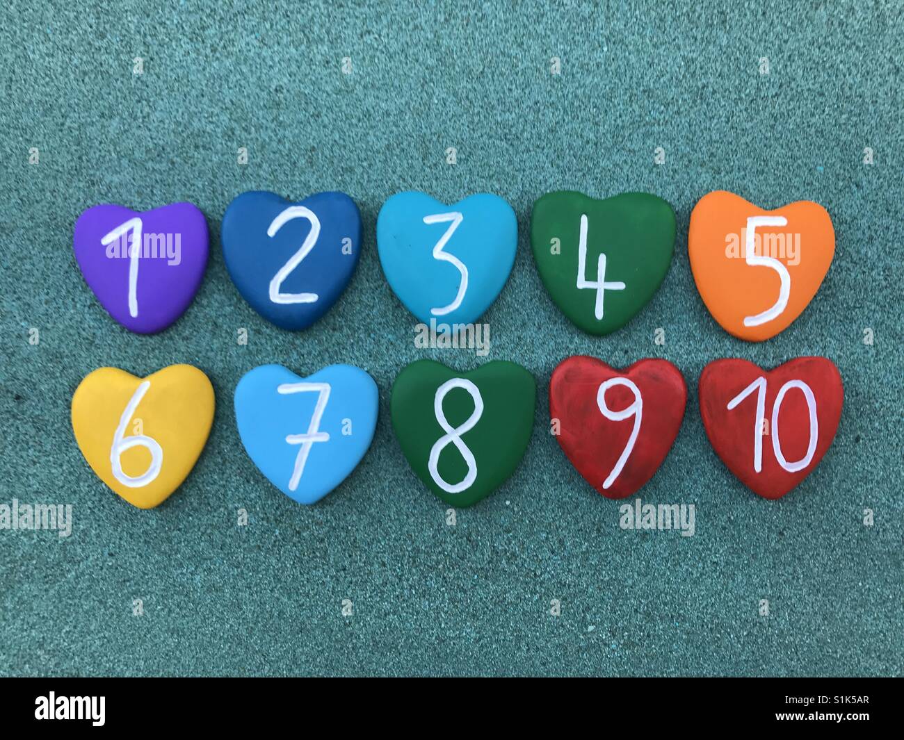 One to ten numbers with heart stones over green sand - Smartphone Captured Stock Image