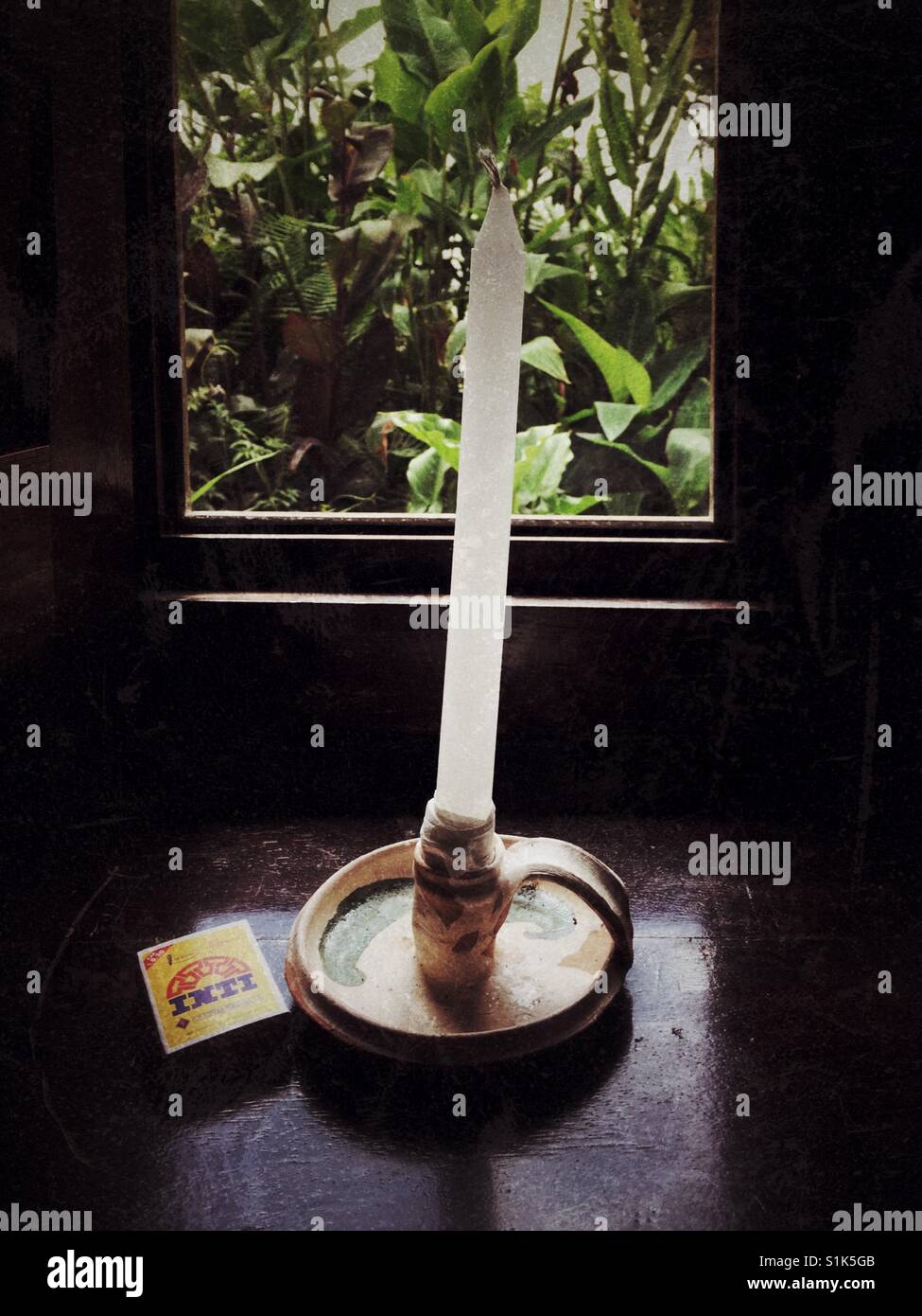 New candle in traditional clay candle holder next to box of matches on a wooden windowsill of hotel in Peru - Smartphone Captured Stock Image