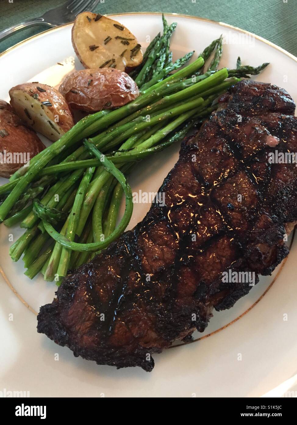 Hearty American meal of steak and potatoes with a side of asparagus, USA - Smartphone Captured Stock Image