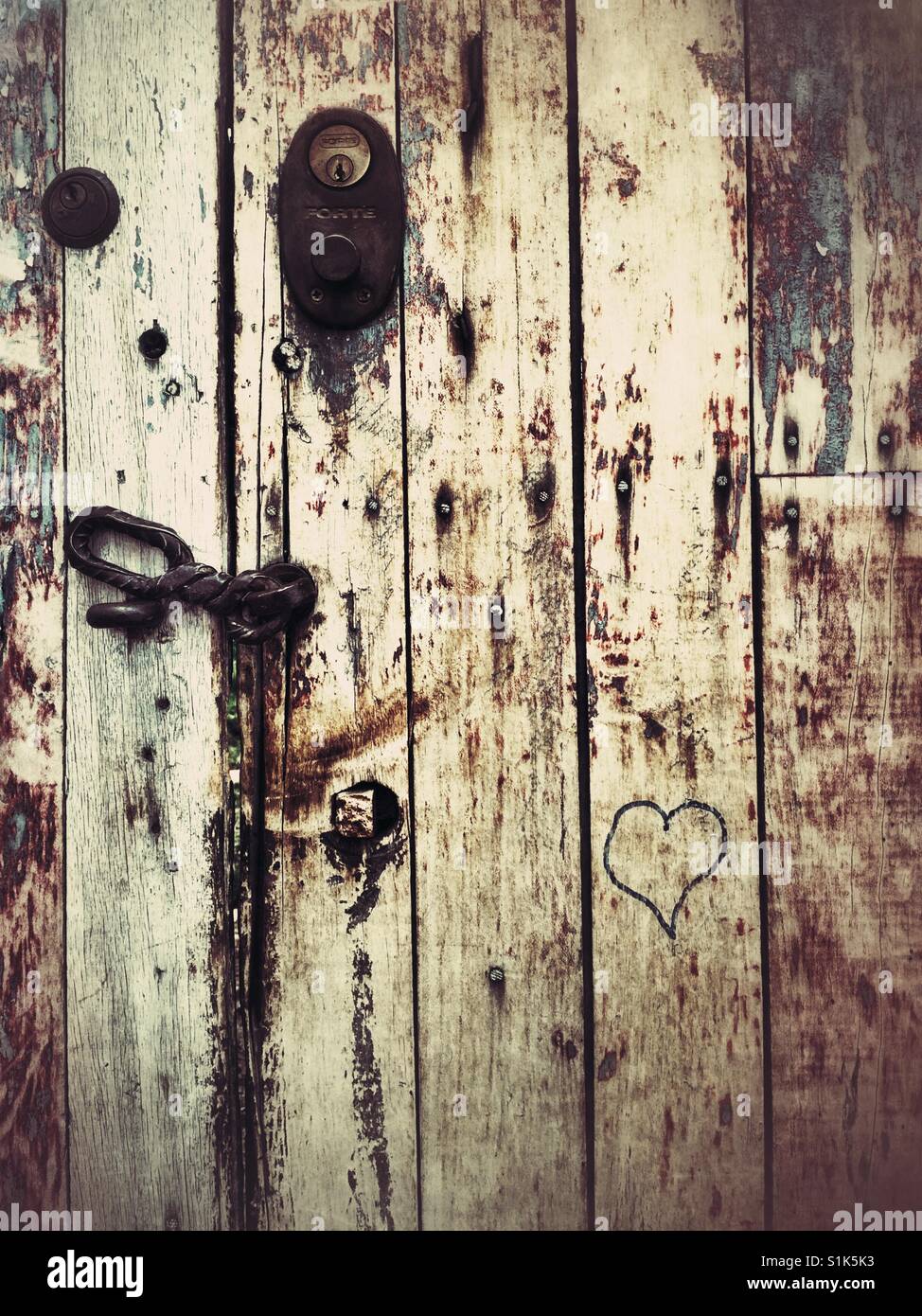 weathered wooden door in Cusco Peru with metal locks and carved heart - Smartphone Captured Stock Image