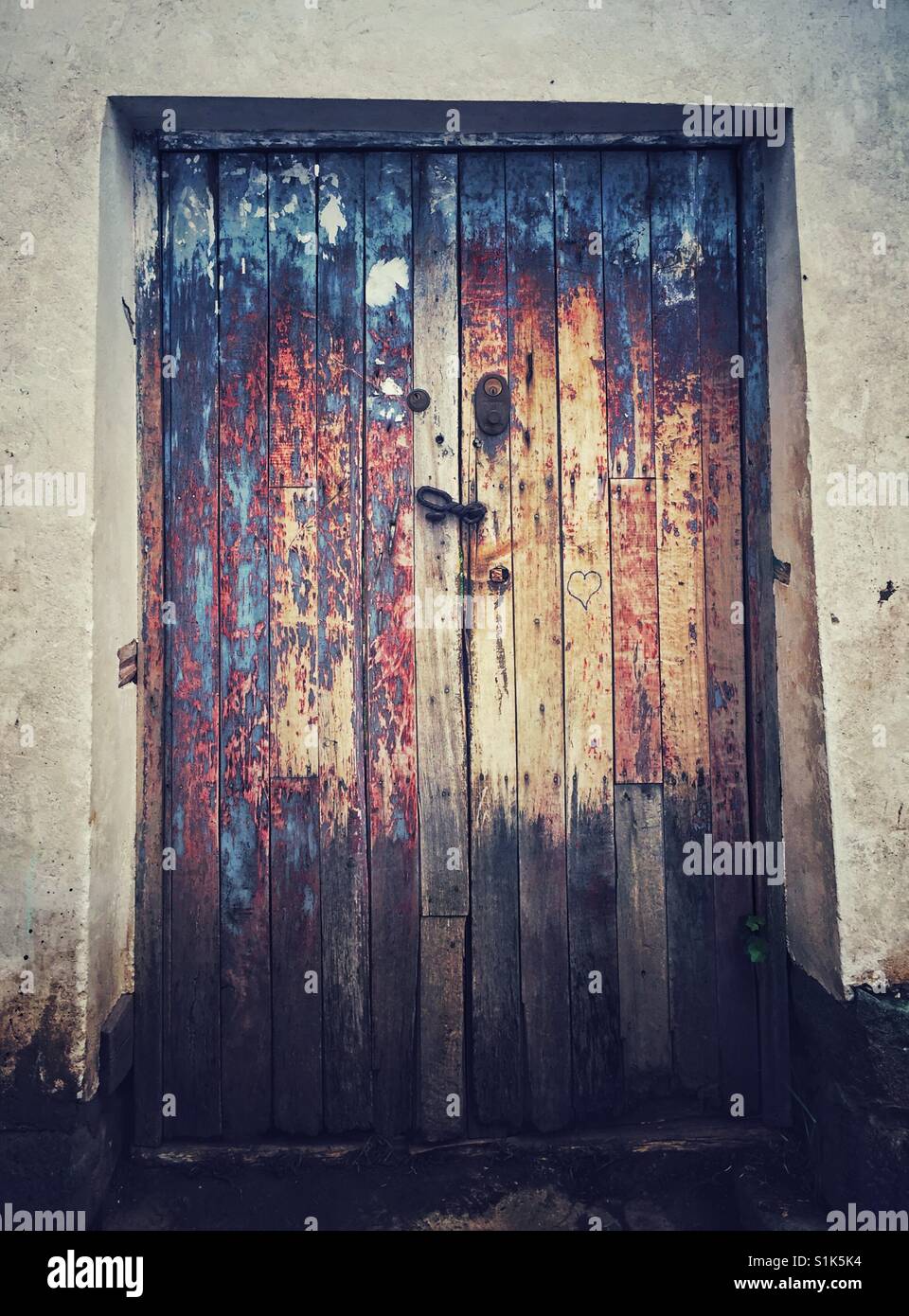 weathered wooden door in Cusco Peru with metal locks and carved heart - Smartphone Captured Stock Image