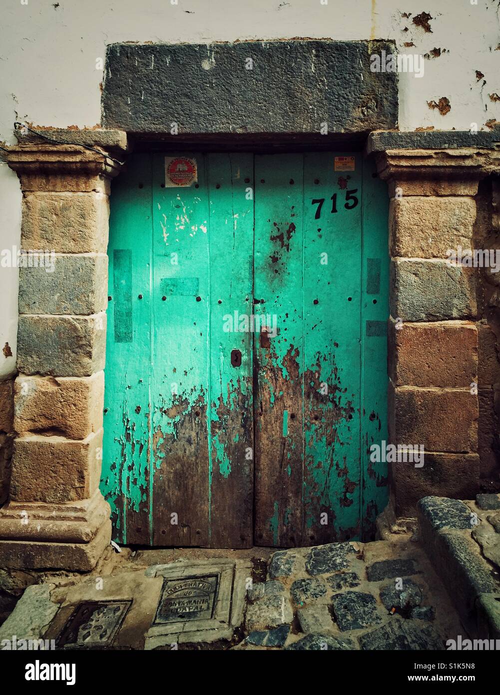 Old weathered aged wooden double,door painted,bright teal green in Cusco, Peru Stock Photo
