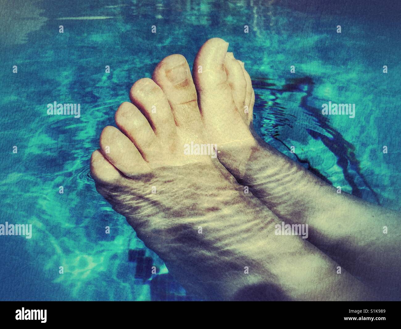Summer fun. Woman's feet in swimming pool, keeping cool - Smartphone Captured Stock Image