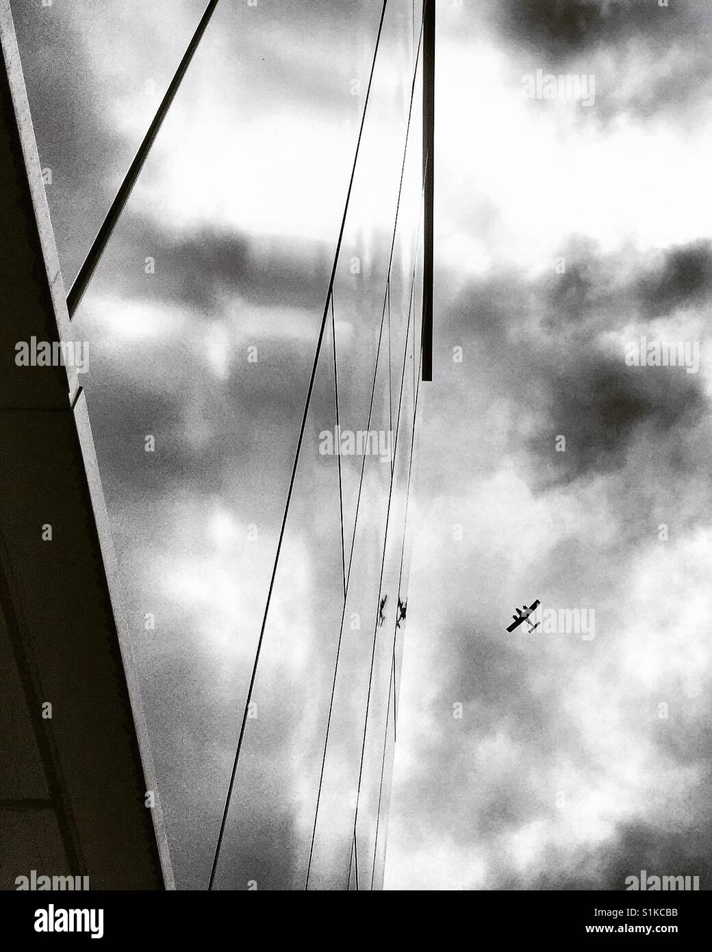 Vintage plane in cloudy sky, reflected in a modern building - Smartphone Captured Stock Image