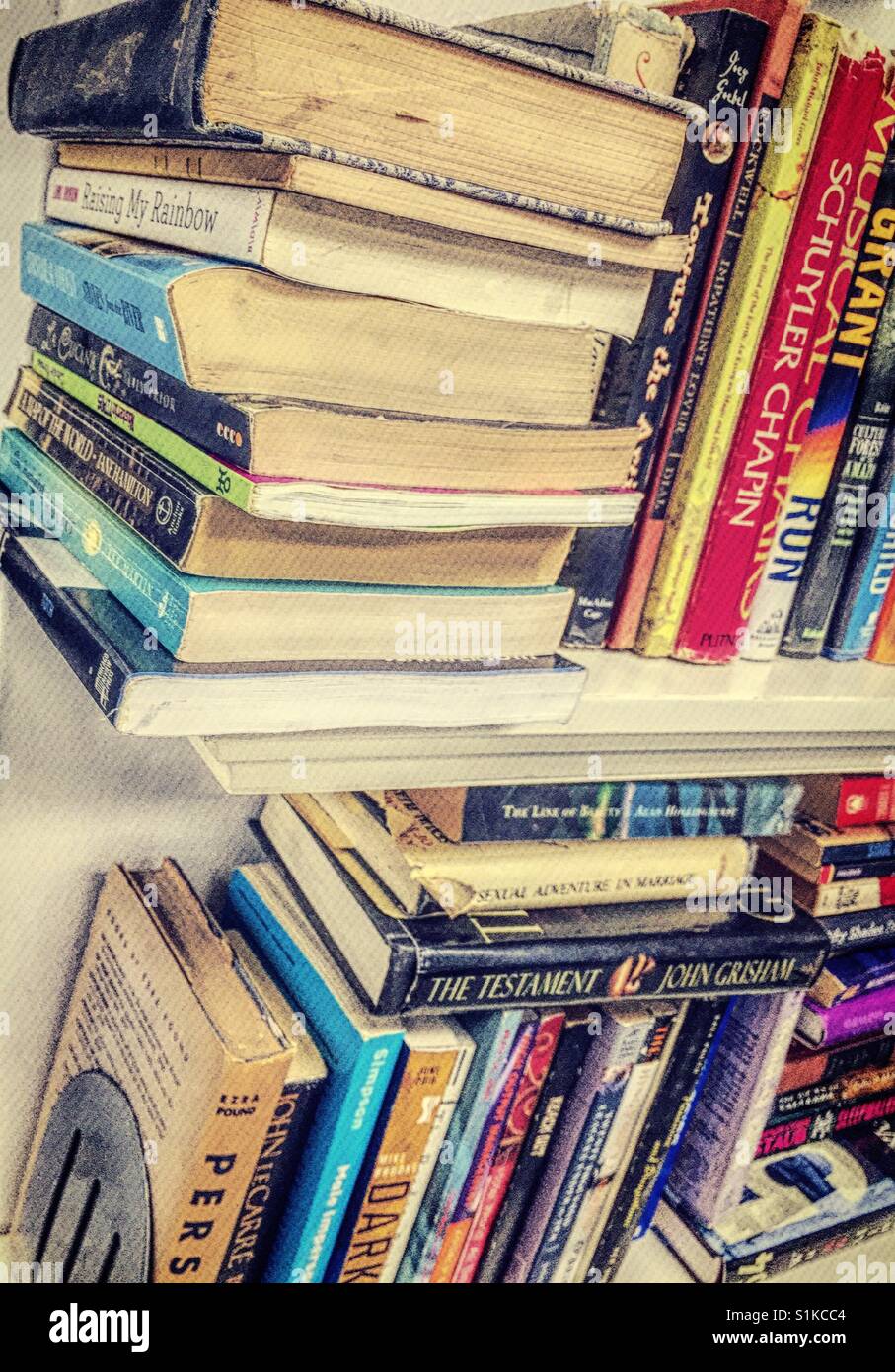 Books, hardback and paperback on cluttered shelves, USA Stock Photo