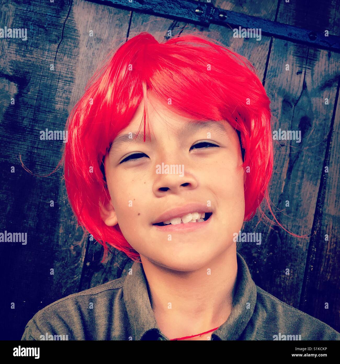young eurasian boy wearing red wig Stock Photo Alamy