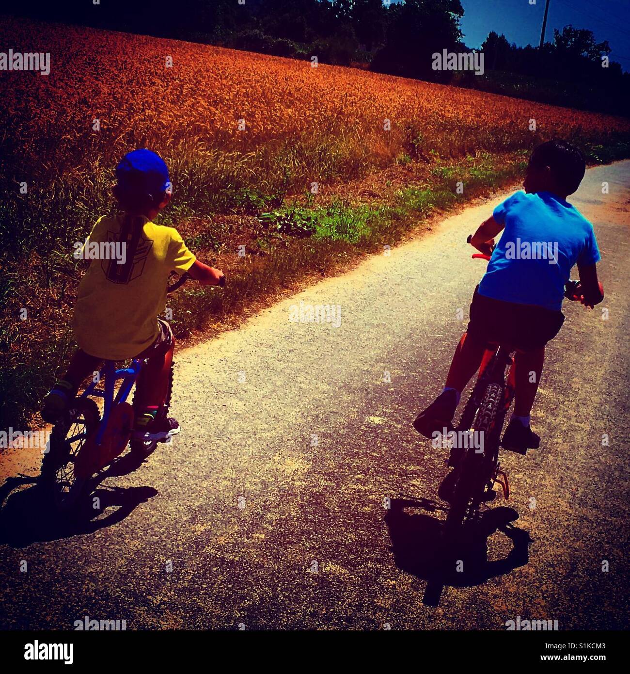 2 boys riding bicycle together side by side on the road - Smartphone Captured Stock Image