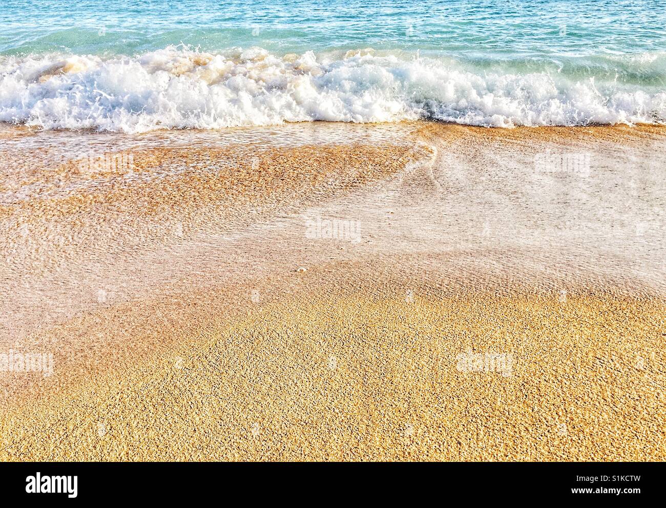 Coastal beach landscape of waves on the sand. Low angle with sand in low 2/3 looking out to sea Stock Photo