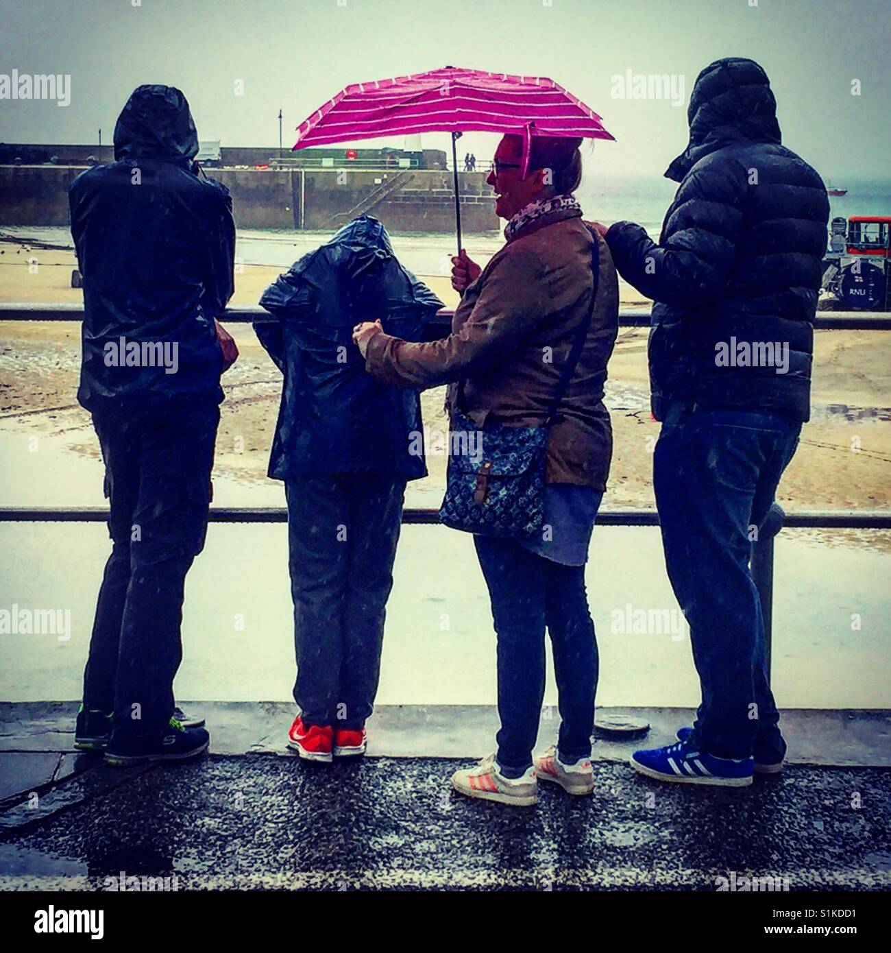 A family stand in the summer rain in St Ives,Cornwall - Smartphone Captured Stock Image