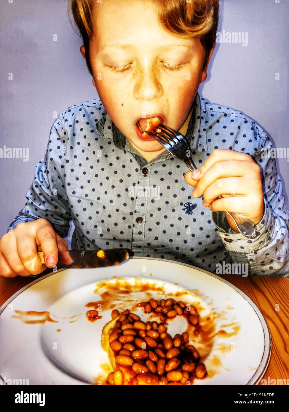 11-year old boy eating beans on toast Stock Photo