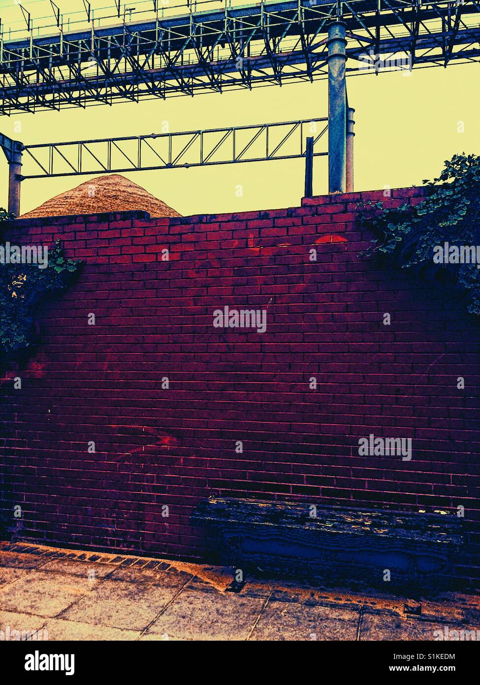 Quarry transportation system and pile of sand behind brick wall, Greenwich Peninsula, London, England - Smartphone Captured Stock Image