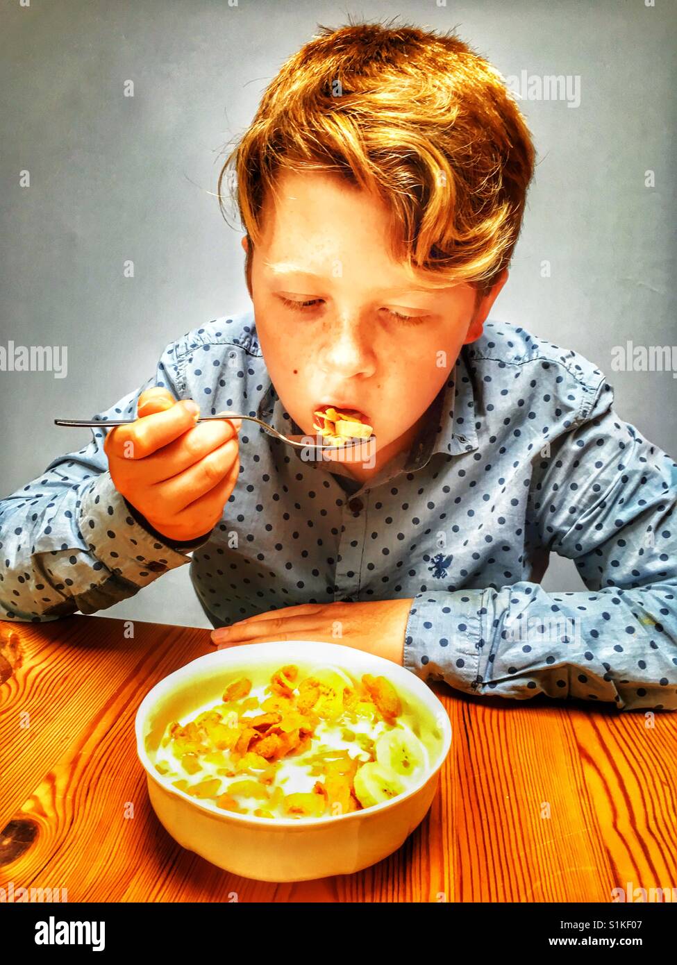 Boy eating cornflakes with banana for breakfast. - Smartphone Captured Stock Image