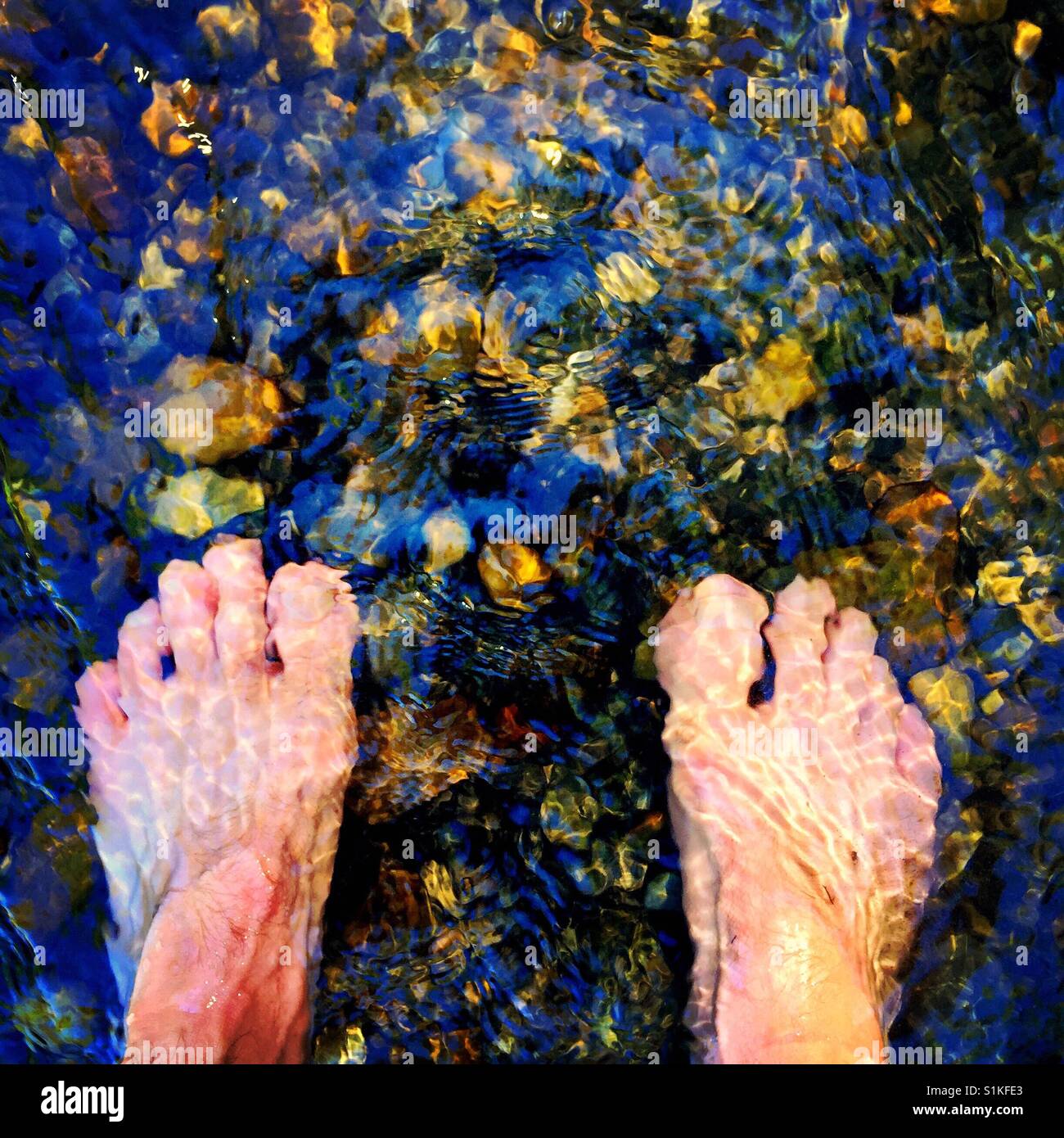Close up of male feet in a shallow mountain stream Stock Photo