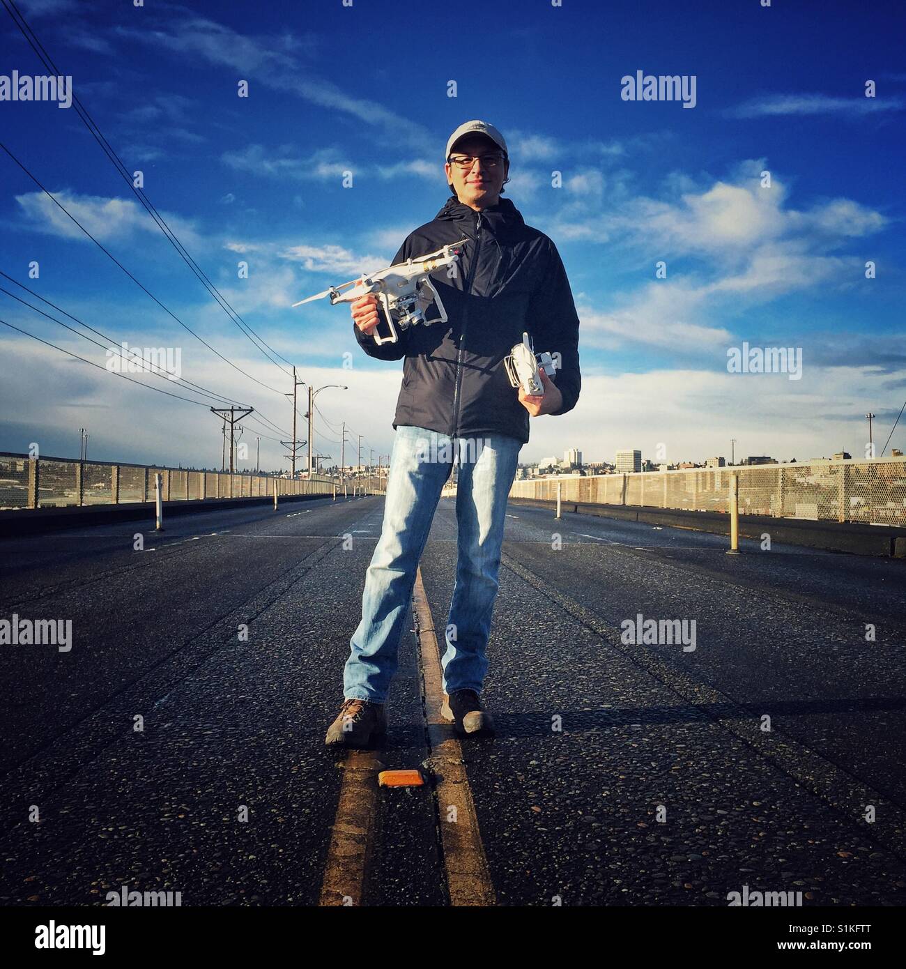 Middle aged asian man holding drone in the middle of the road Stock Photo
