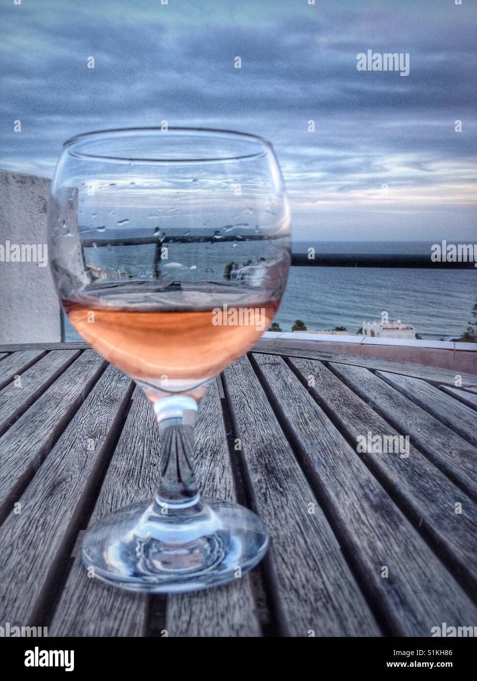 Wine glass with rosé wine and ocean background. Stock Photo