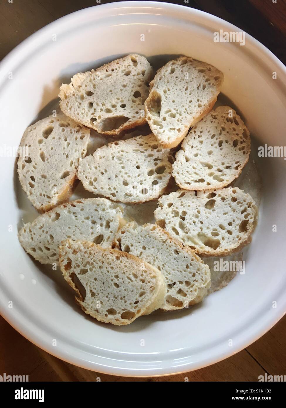 Slices of bread soaked in milk in preparation for french toast Stock Photo