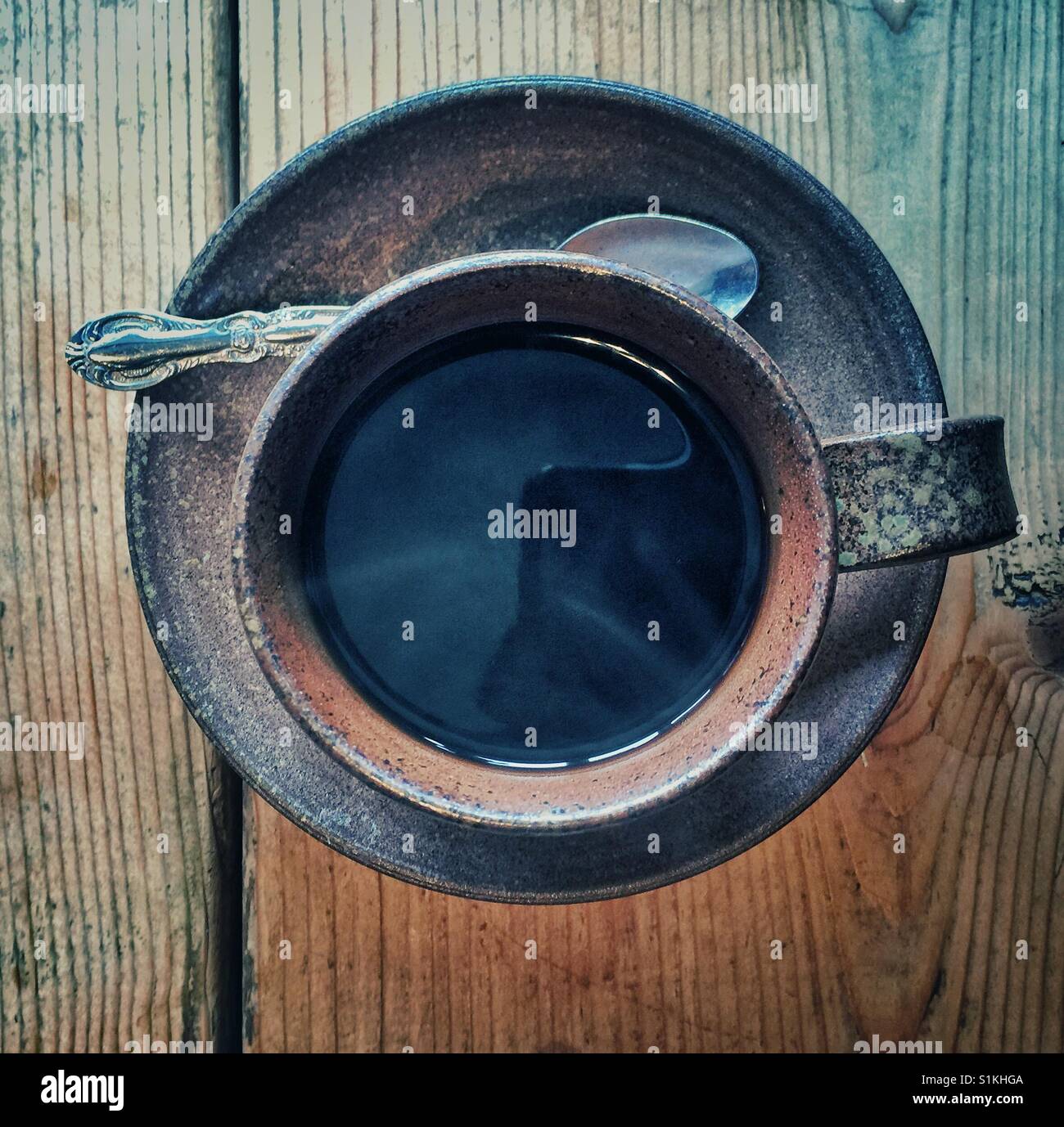 Black coffee in dark brown stoneware clay cup on wooden table - Smartphone Captured Stock Image