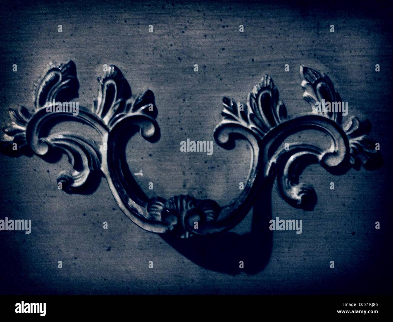 Baroque curlicue in blue- filtered photo of dresser drawer pull - Smartphone Captured Stock Image