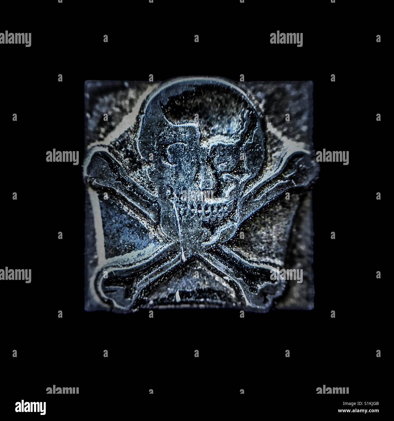 Grungy metal skull and cross bones printers stamp block - Smartphone Captured Stock Image