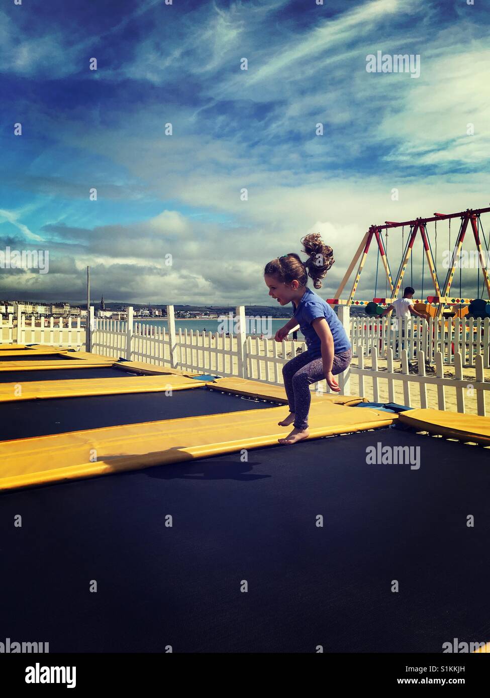 Little girl on trampoline by seaside Stock Photo