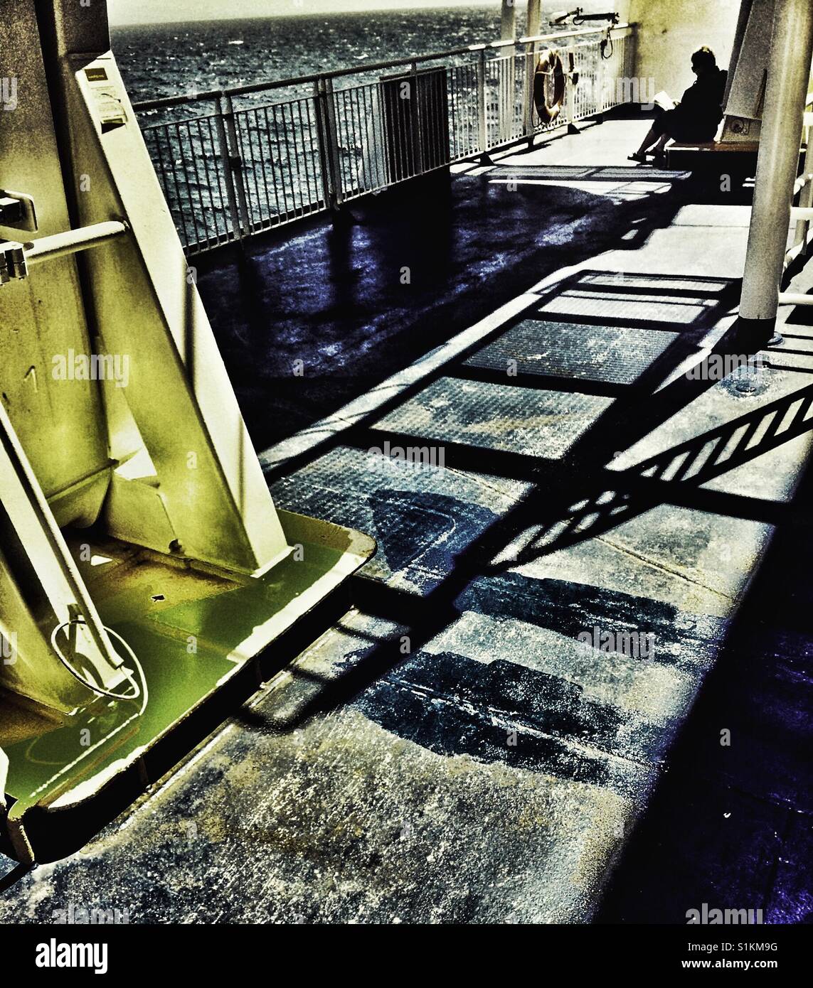 Woman reading alone on outer deck of ferry, Canada Stock Photo