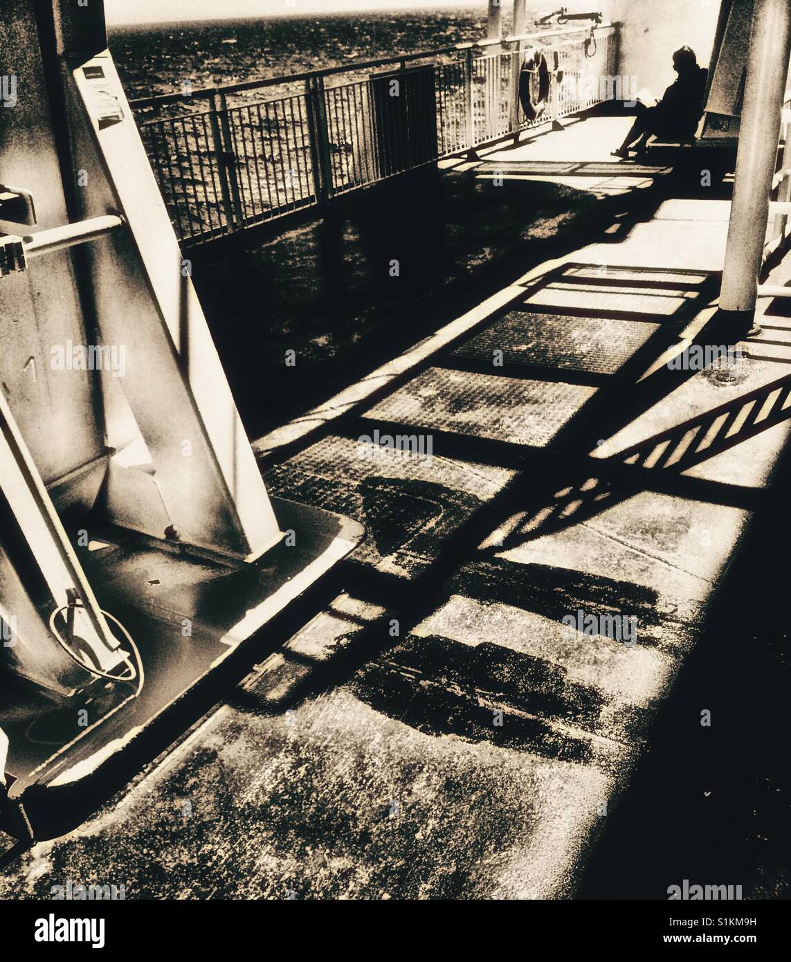 Woman reading alone on outer deck of ferry, Canada Stock Photo