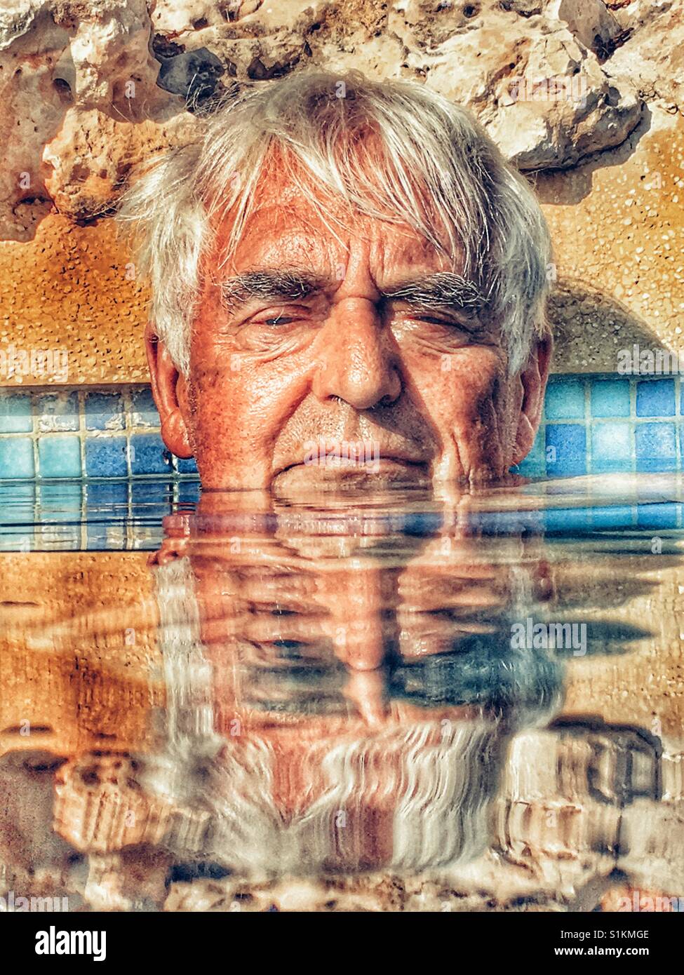 Senior man, keeping cool in a swimming pool. - Smartphone Captured Stock Image