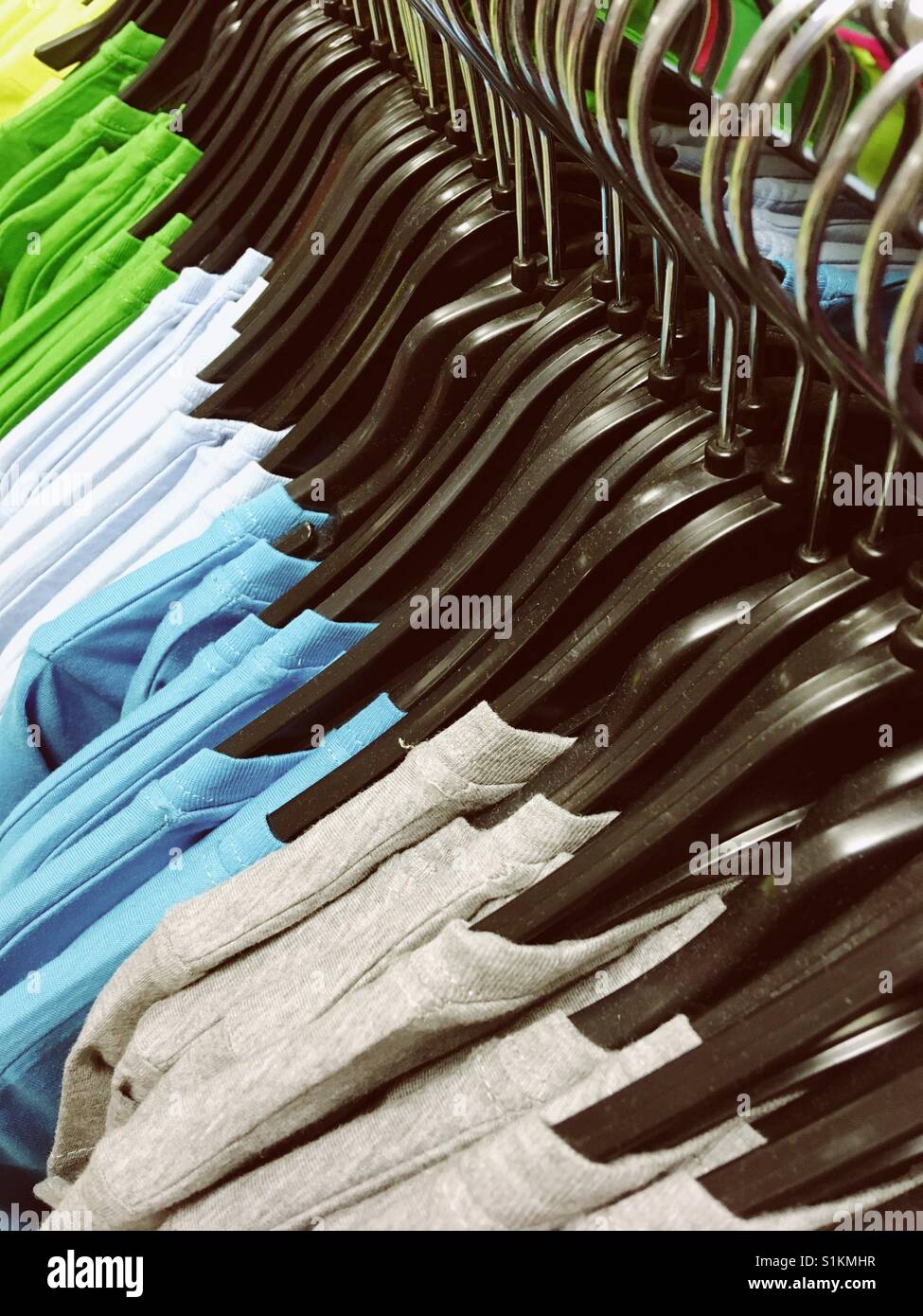 Colourful T-shirts on hangers for sale in a store Stock Photo