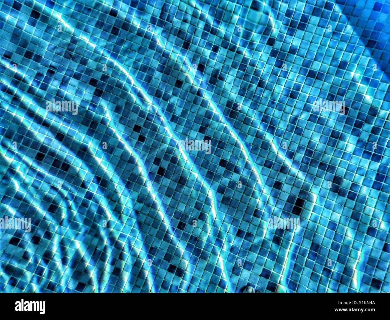 Light refractions in the water of a blue tiled swimming pool - Smartphone Captured Stock Image