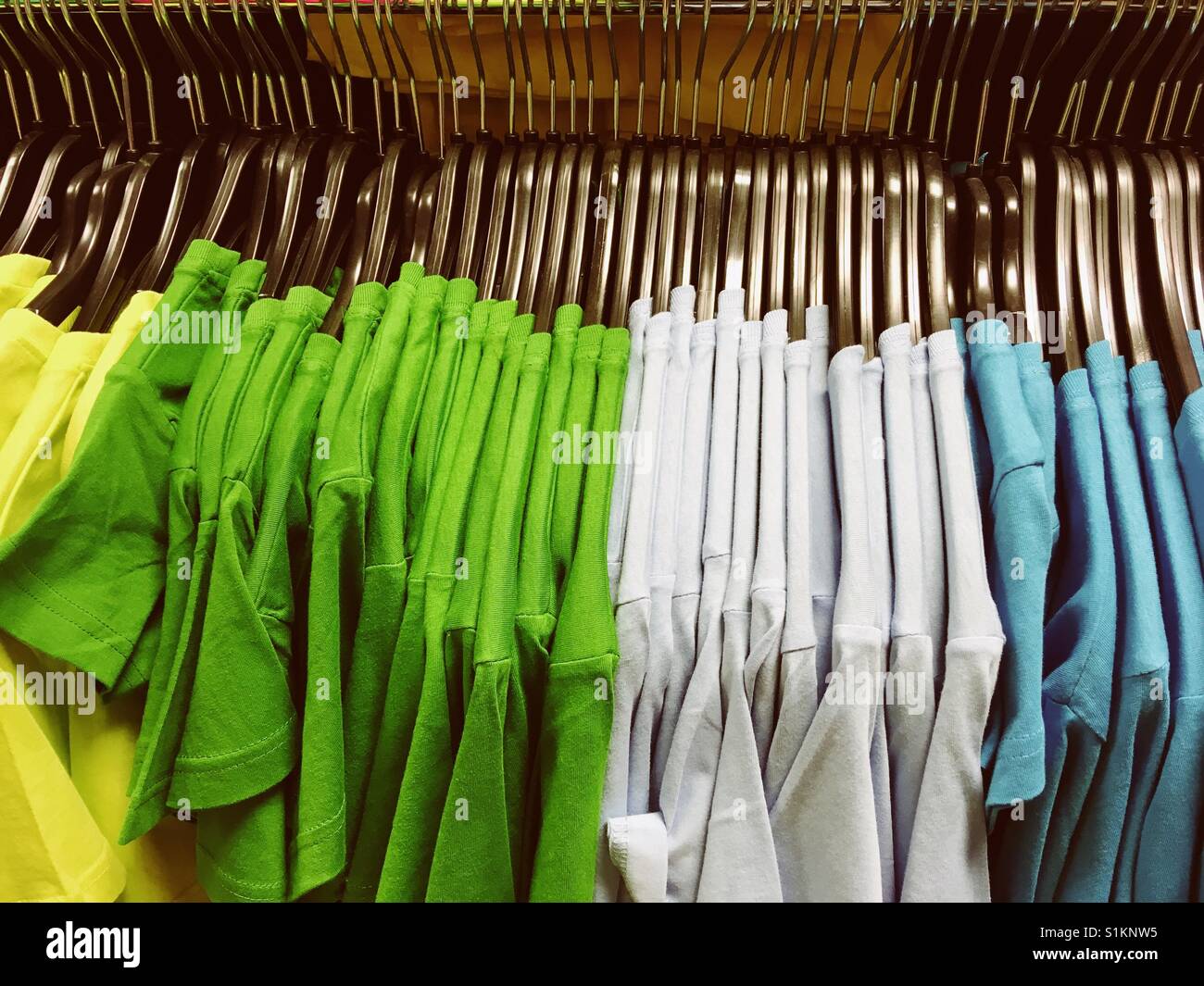 Colourful t-Shirts on clothes hangers Stock Photo
