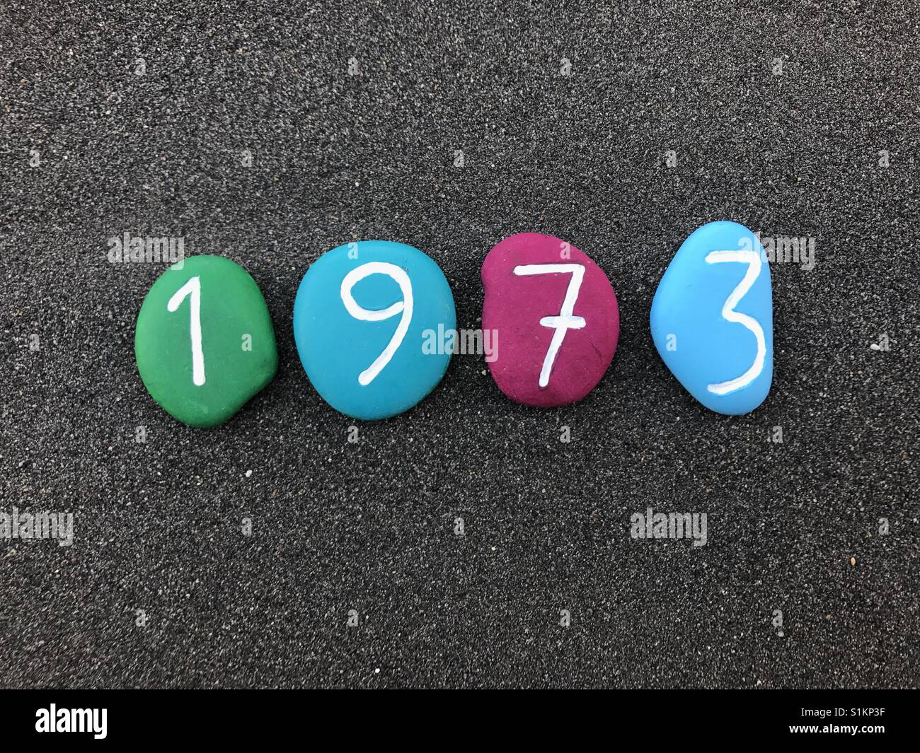1973 year with colored stones over black volcanic sand Stock Photo