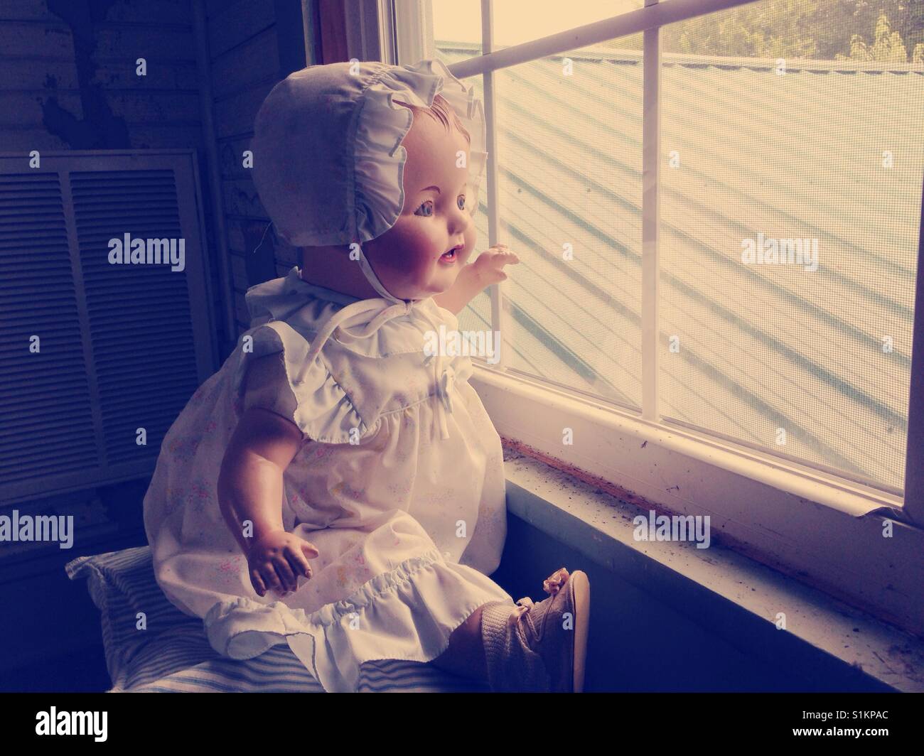 Window watching- Doris the composition doll watches eagerly out the upstairs window for Papa - Smartphone Captured Stock Image