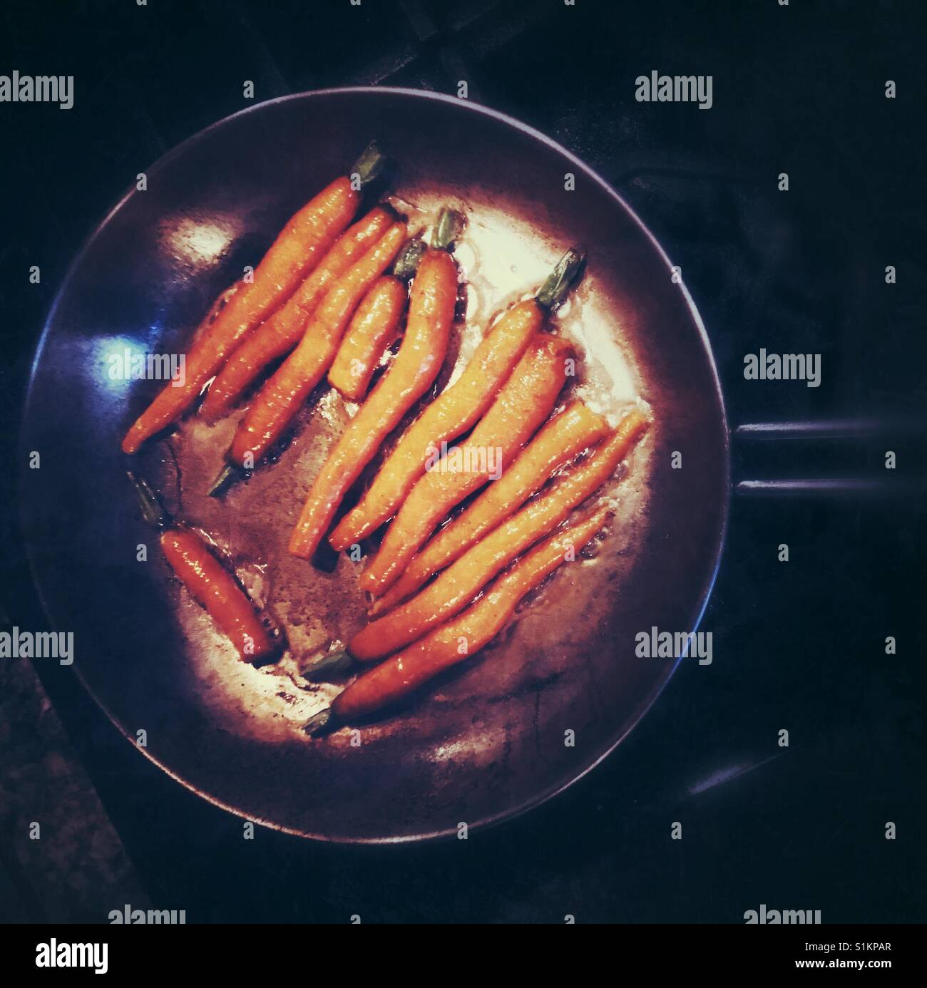 Seasonal fresh carrots simmering in butter in a pan. - Smartphone Captured Stock Image