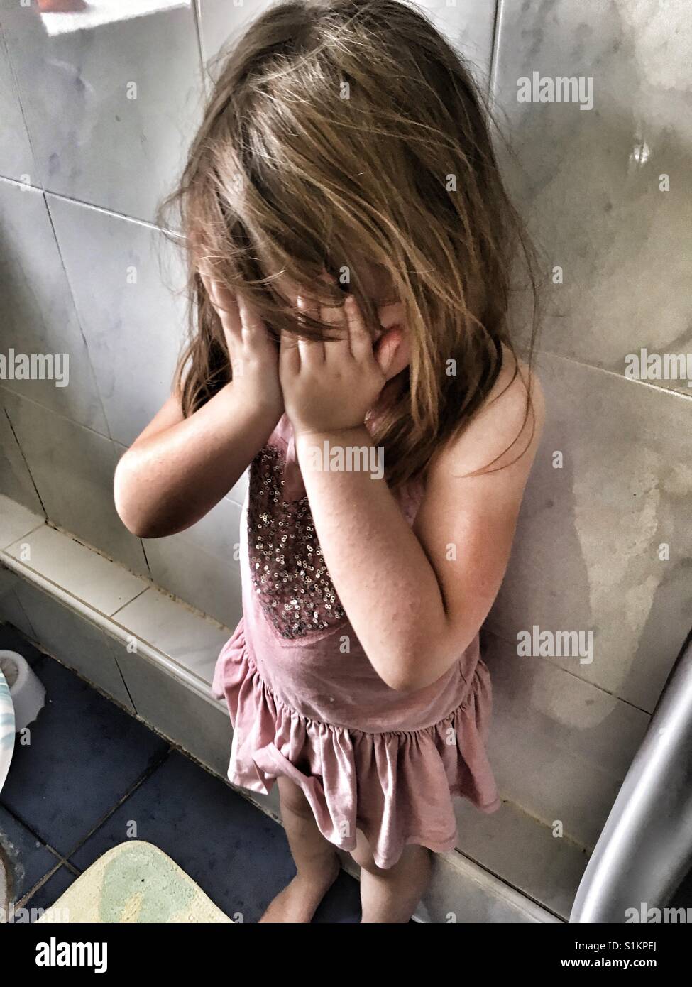 Girl crying with her hands covering her face. Stock Photo