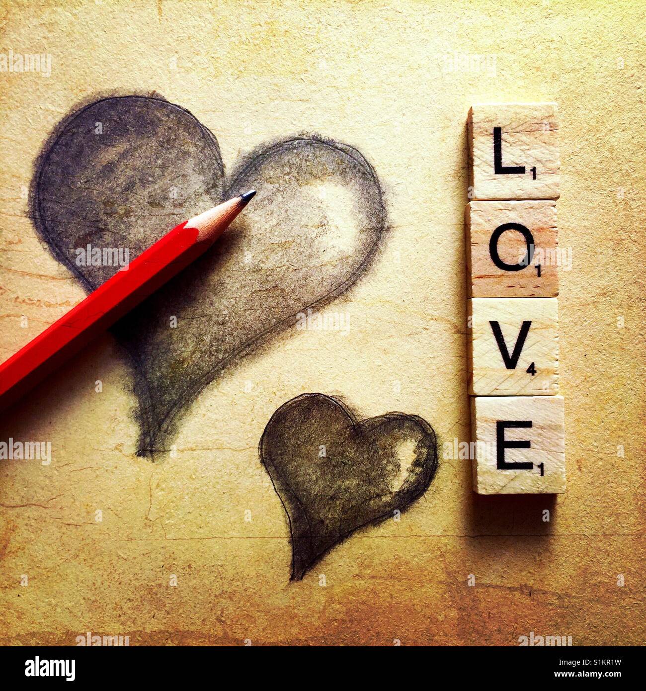 A simple pencil drawing of two hearts with a pencil and the word love spelled out with wooden letters Stock Photo