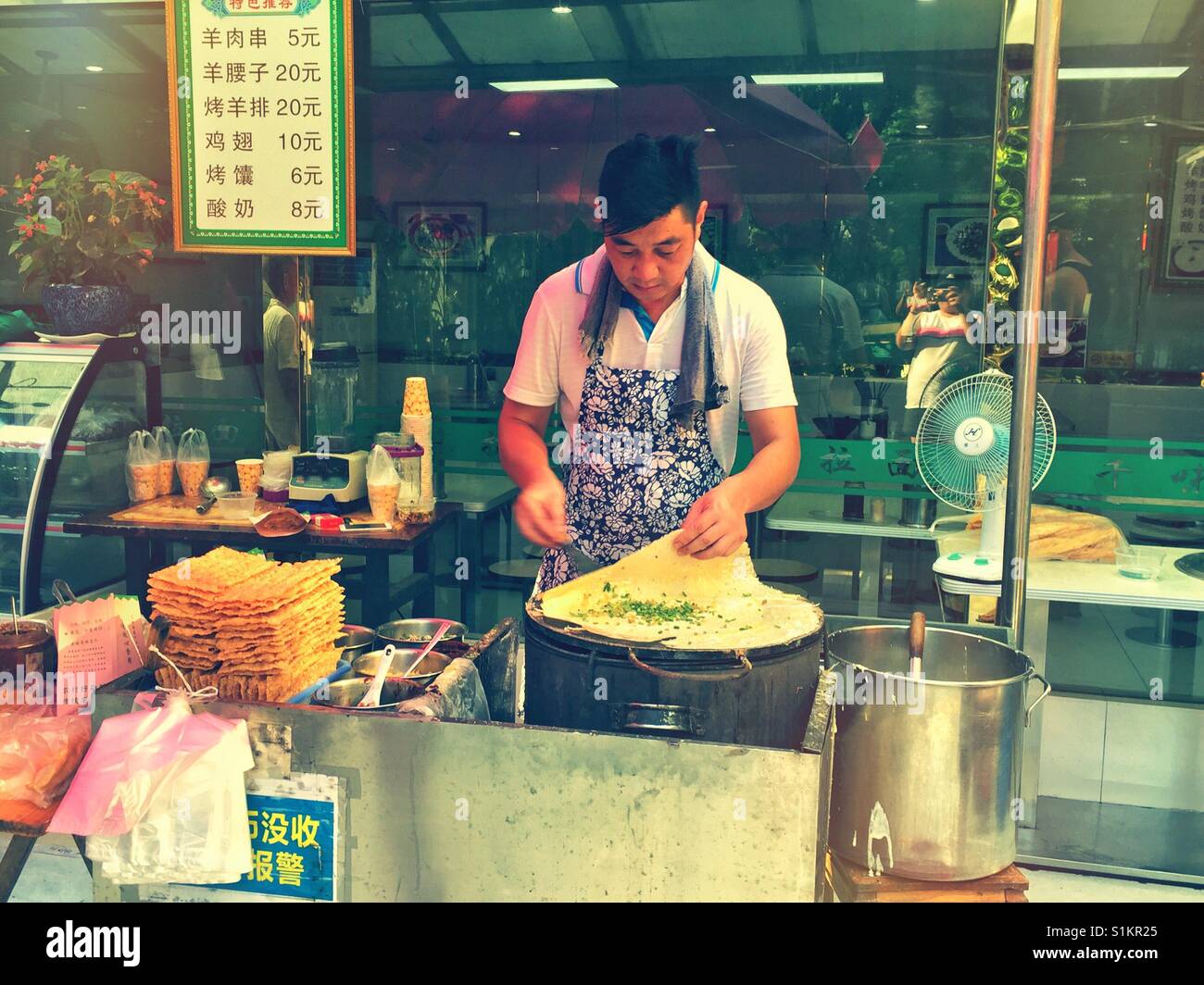 A man cooking egg pancakes on a street food stall in Shanghai, China. - Smartphone Captured Stock Image