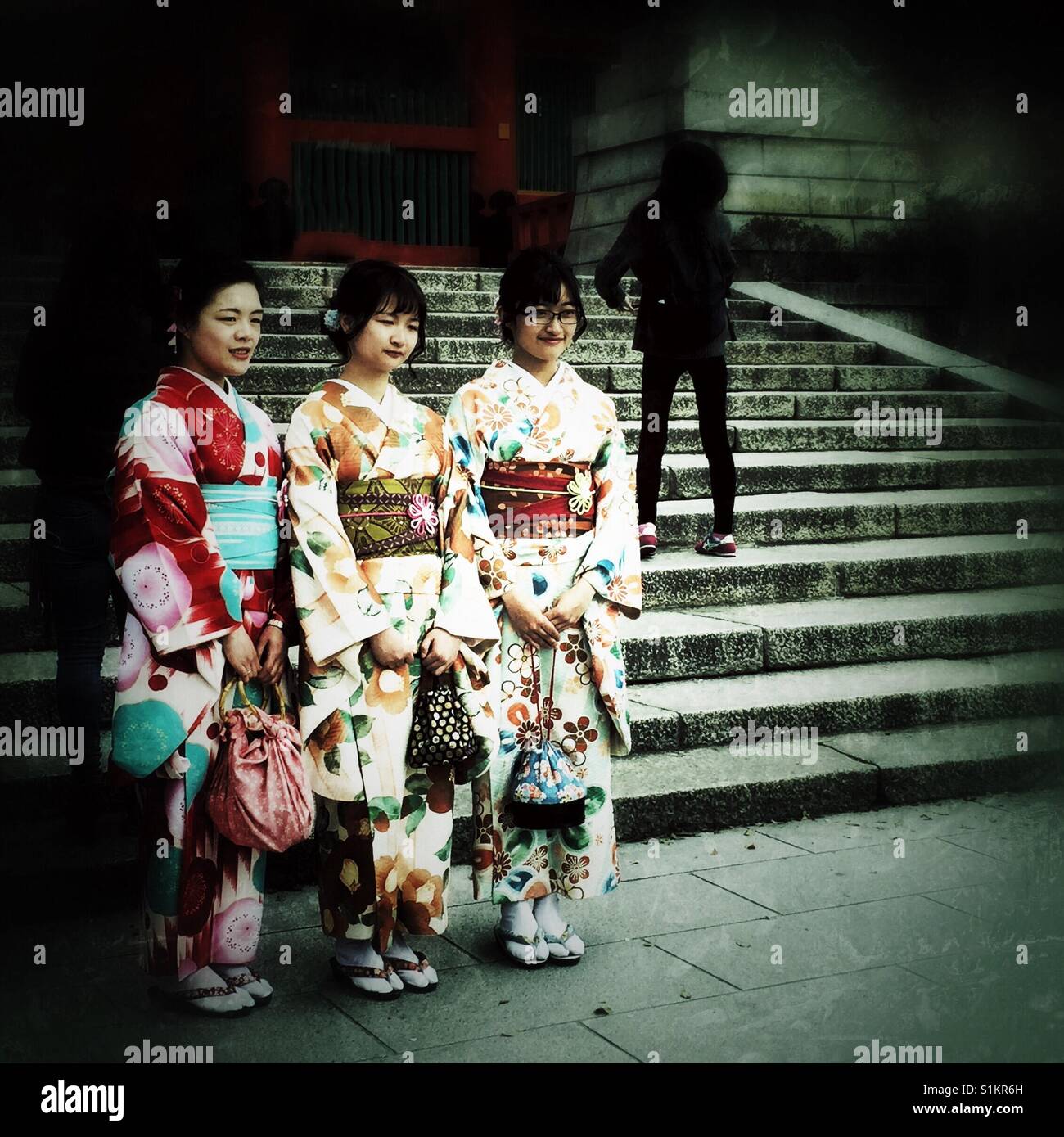 Three Japanese girls dressed in kimonos pose for the picture in Kyoto Stock Photo