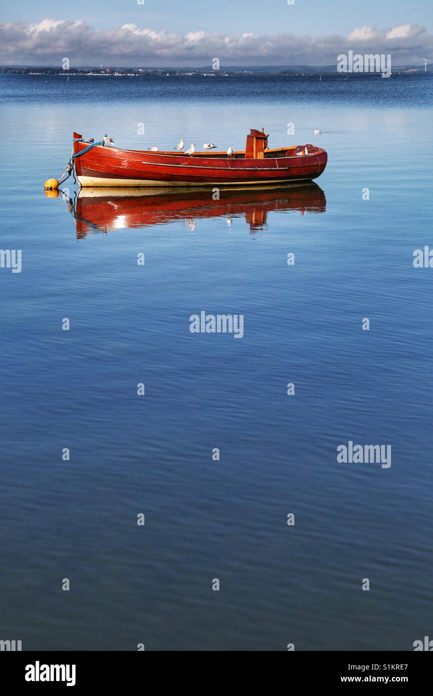 Red boat mirrored in water Stock Photo